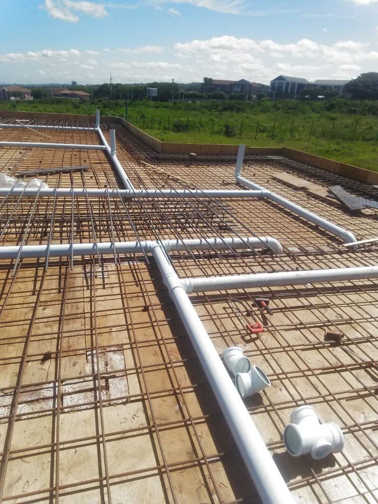 White drainage pipes laid over steel reinforcing mesh on a new building slab